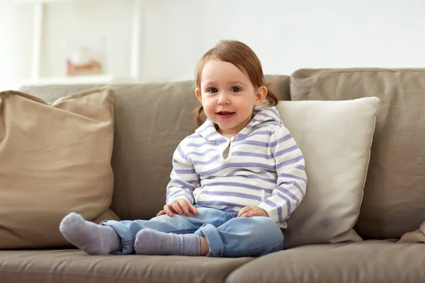 Feliz niña sonriente sentada en el sofá en casa —  Fotos de Stock