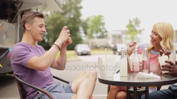 Мужчина фотографирует друзей, которые едят в фургоне с едой — стоковое видео