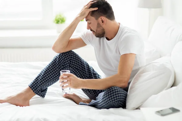 Homme au lit avec verre d'eau à la maison — Photo