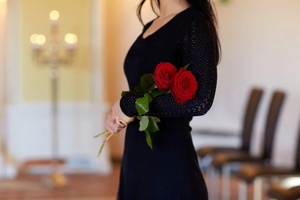 Woman with red roses at funeral in church — Stock Photo, Image