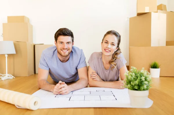 Couple with boxes and blueprint moving to new home — Stock Photo, Image