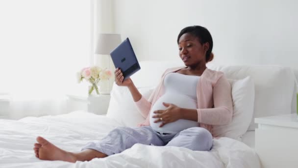 Happy těhotná žena s tablet pc v posteli — Stock video