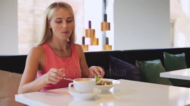 Mujer comiendo y bebiendo café en el restaurante — Vídeos de Stock