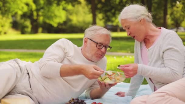 Pareja mayor comiendo ensalada en el picnic en el parque — Vídeo de stock