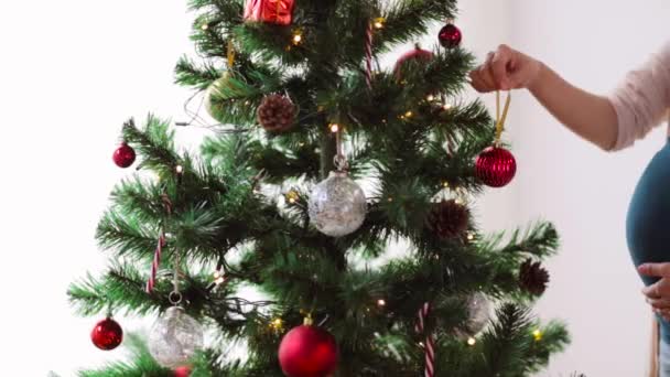 Zwangere vrouw versieren kerstboom thuis — Stockvideo