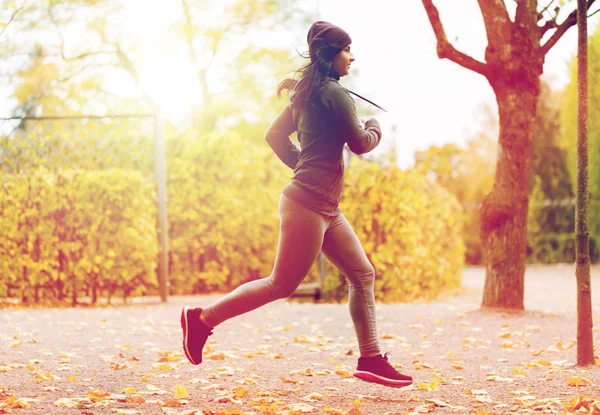 Close up of young woman running in autumn park — Stock Photo, Image