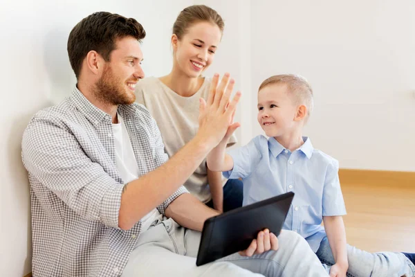 Family with tablet pc at new home making high five — Stock Photo, Image