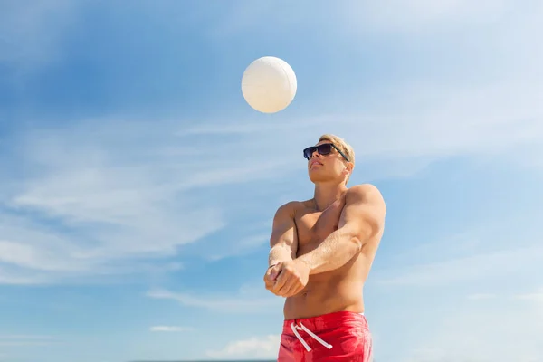 Mladý muž s míčem hraje volejbal na pláži — Stock fotografie
