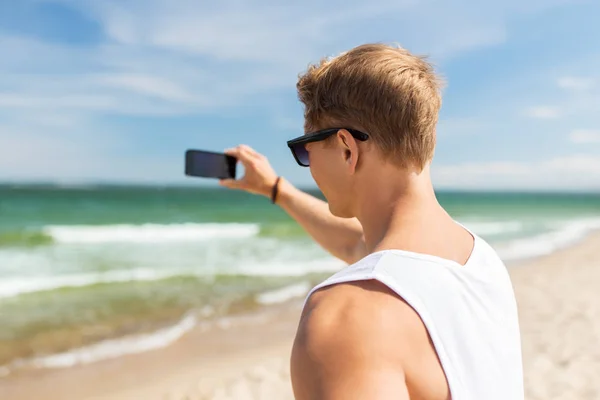 Man with smartphone photographing on summer beach — Stock Photo, Image