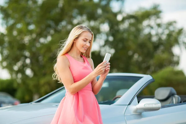 コンバーチブル車でスマート フォンを持つ若い女性 — ストック写真