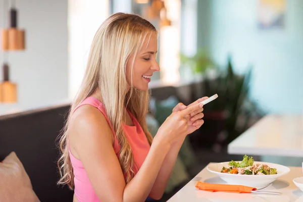 Mujer feliz con smartphone comiendo en el restaurante — Foto de Stock