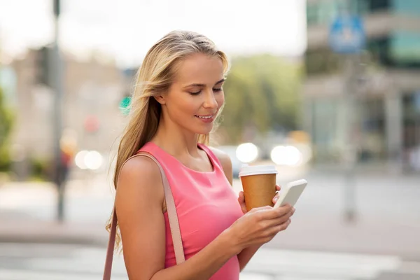 Woman with coffee and smartphone in city — Stock Photo, Image