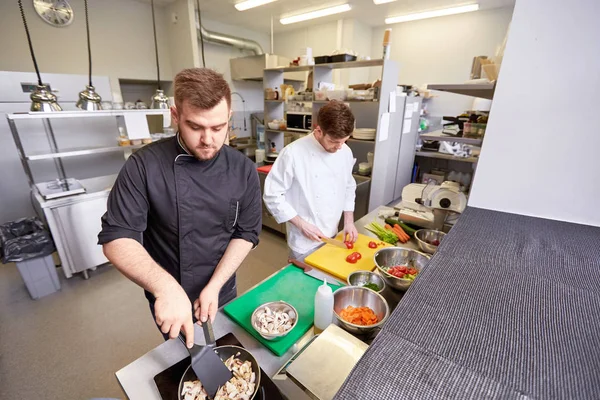 Cocinero y cocinar comida en la cocina del restaurante — Foto de Stock