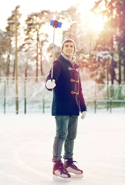 Glücklicher junger Mann mit Smartphone auf Eisbahn — Stockfoto