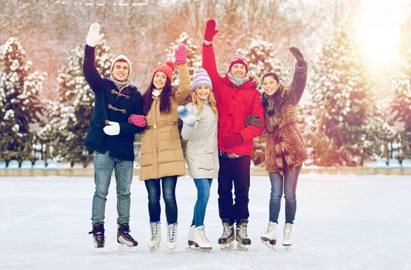 Happy přátelé bruslení na kluzišti venku — Stock fotografie