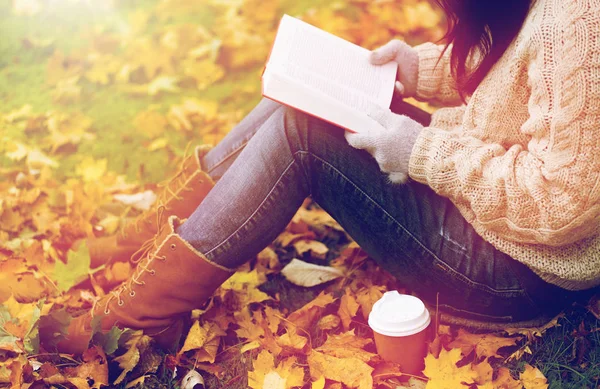 Frau mit Buch trinkt Kaffee im Herbstpark — Stockfoto