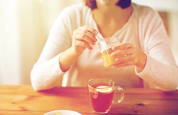 Close up of ill woman drinking tea with honey — Stock Photo, Image