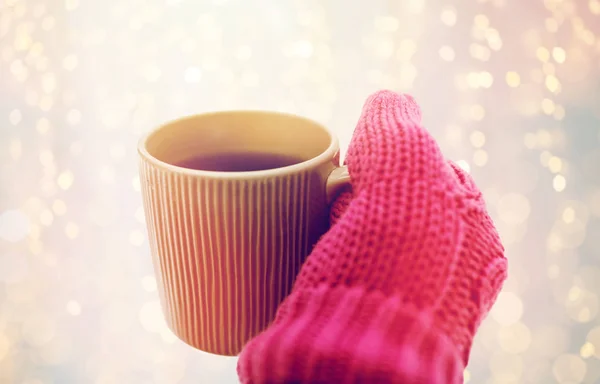 Fechar a mão no inverno mitene segurando caneca de chá — Fotografia de Stock