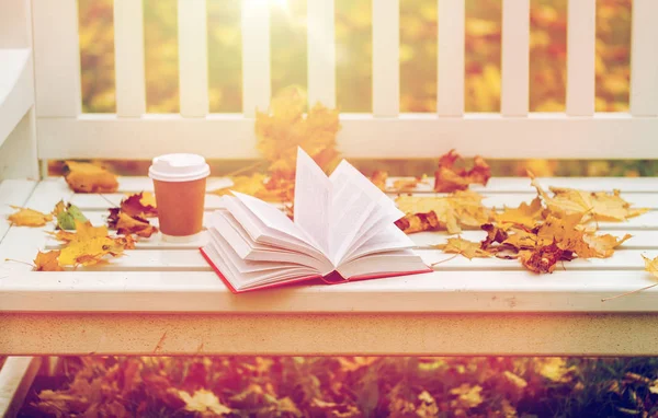 Libro aperto e tazza di caffè sulla panca nel parco autunnale — Foto Stock