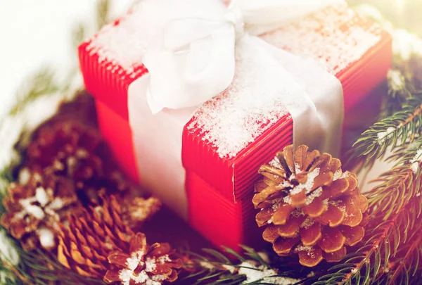 Закрытие рождественского подарка и елового венка на снегу — стоковое фото