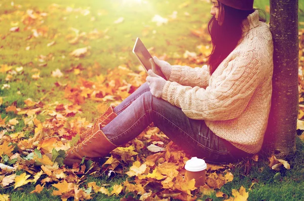 Vrouw met tablet pc en koffie in de herfst park — Stockfoto