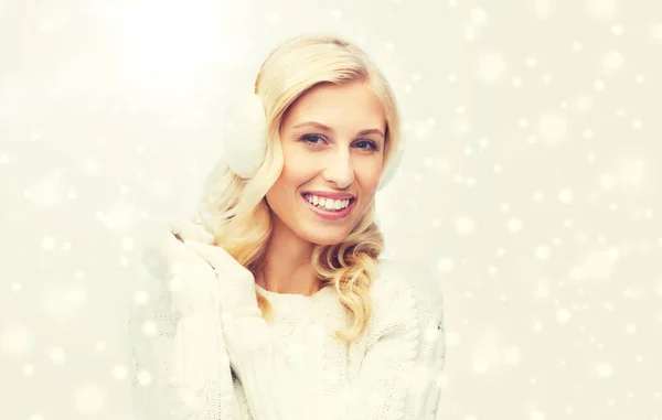 Lachende jonge vrouw in winter oorkappen en trui — Stockfoto
