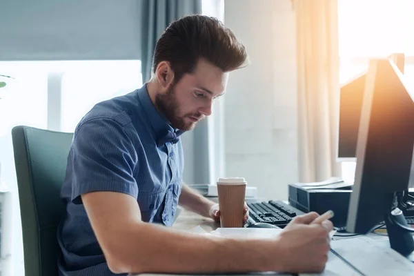 Creative male office worker with coffee writing — Stock Photo, Image