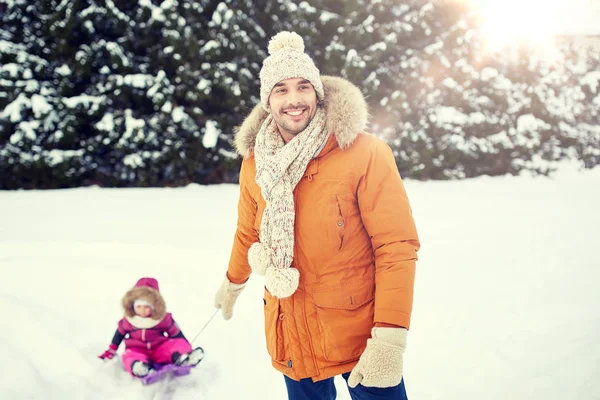 Щасливий чоловік, що носить маленьку дитину на санчатах взимку — стокове фото