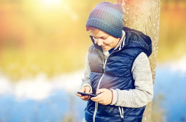 Glücklicher Junge spielt Spiel auf Smartphone im Freien — Stockfoto