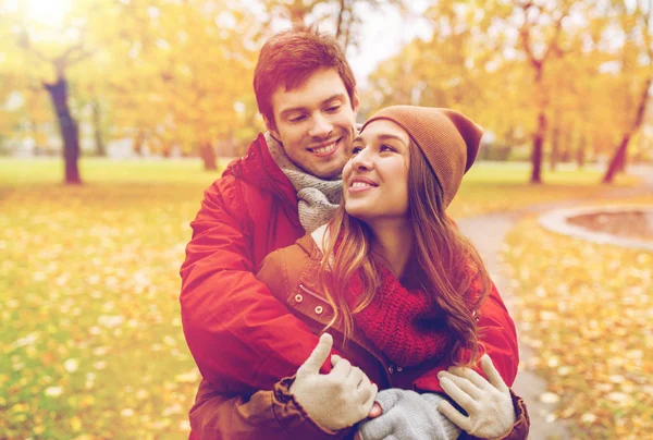 Счастливая молодая пара обнимается в осеннем парке — стоковое фото