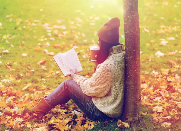 Frau mit Buch trinkt Kaffee im Herbstpark — Stockfoto