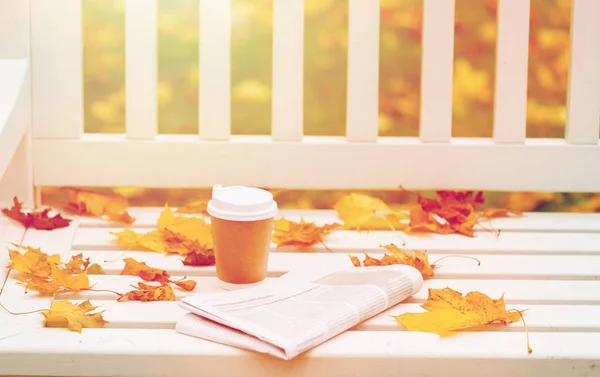Gazety i coffee cup na ławce w parku jesień — Zdjęcie stockowe