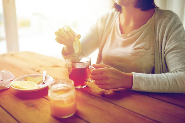 Gros plan de la femme ajoutant du citron à la tasse de thé — Photo