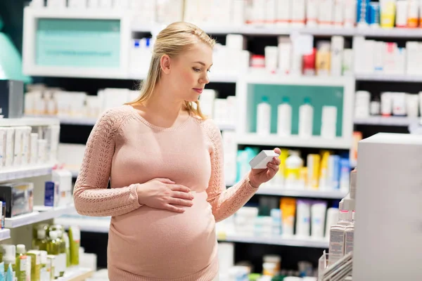 Gelukkig zwangere vrouw met medicatie bij apotheek — Stockfoto