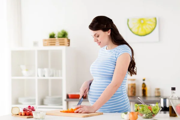 Pregnant woman cooking vegetable salad at home — Stock Photo, Image