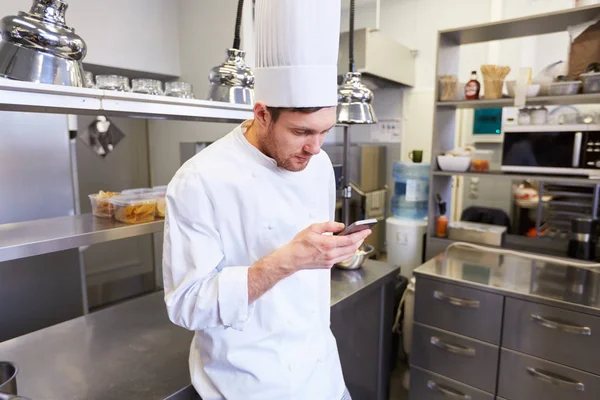 Chef-kok koken met smartphone bij restaurant keuken — Stockfoto