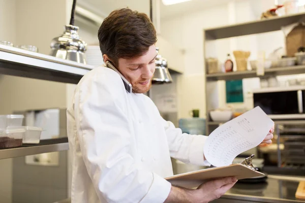 Chef cocinero llamando en smartphone en la cocina del restaurante — Foto de Stock