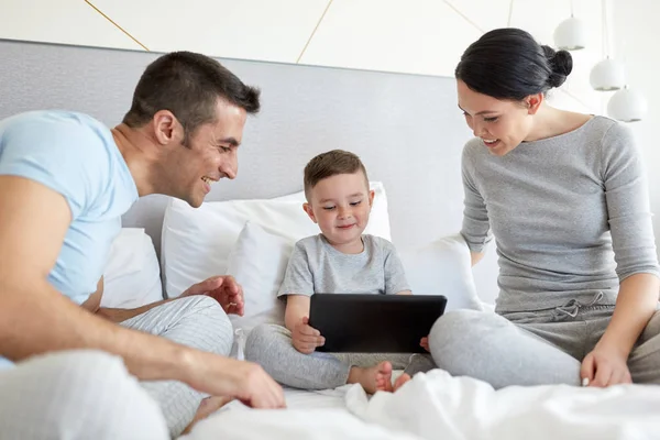 Boldog család-val tabletta pc az ágyban otthon — Stock Fotó