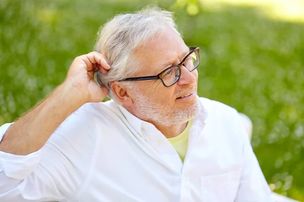 Gelukkig senior man in glazen zitten in zomer park — Stockfoto