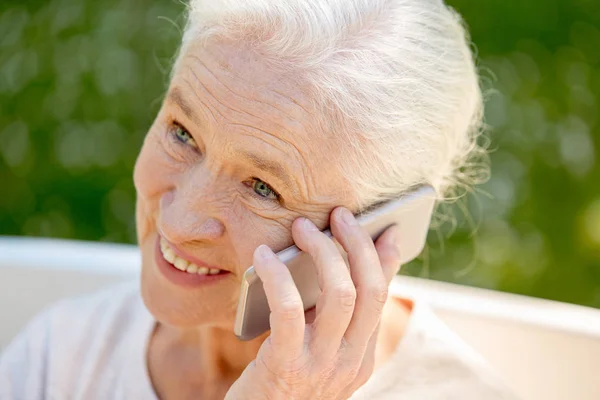 Щаслива старша жінка телефонує на смартфон влітку — стокове фото