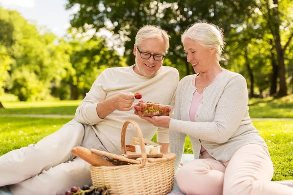 Coppia anziana con fragole al picnic nel parco — Foto Stock
