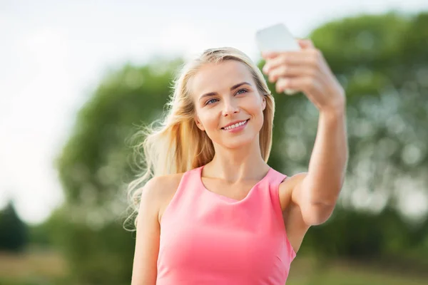 Счастливая женщина делает селфи со смартфоном на улице — стоковое фото