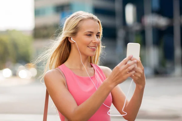 Happy young woman with smartphone and earphones — Stock Photo, Image