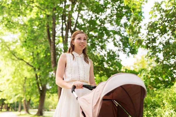Щаслива мати з дитиною в колясці в літньому парку — стокове фото