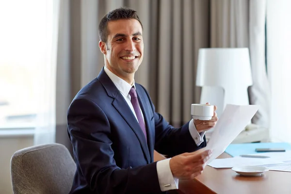 Zakenman met papieren koffie drinken bij hotel Stockfoto