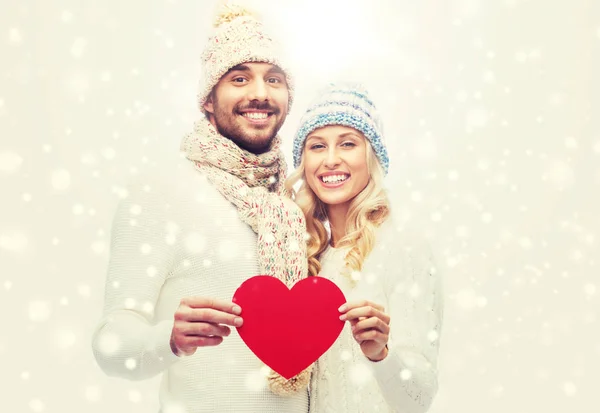 Smiling couple in winter clothes with red heart — Stock Photo, Image