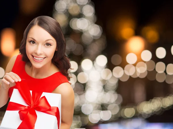 Noel hediye kutusu ile Kırmızı elbiseli gülümseyen kadın — Stok fotoğraf