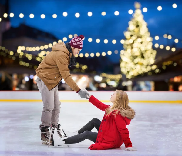 Homme aidant femme sur la patinoire de Noël — Photo