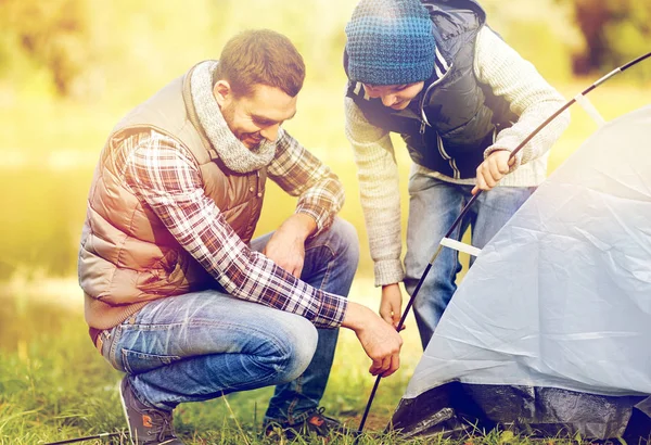 Happy father and son setting up tent outdoors — Stock Photo, Image