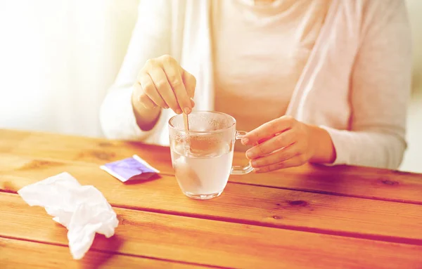 Woman stirring medication in cup with spoon — Stock Photo, Image